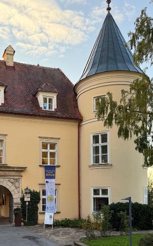 Teil vom Bildungshaus Schloss St. Martin und einer Fahne mit Erasmuslogo