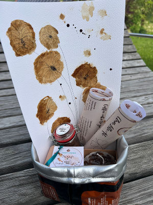 Eine liebevoll zusammengestellte Kaffee-Box welche verschiedene Produkte enthält - darunter Coffee Cake to go, Kaffee-Seife, Kaffee-Kerzen, ein Rezeptblatt sowie einen QR-Code zum eigenen Latte-Art-Tutorial.