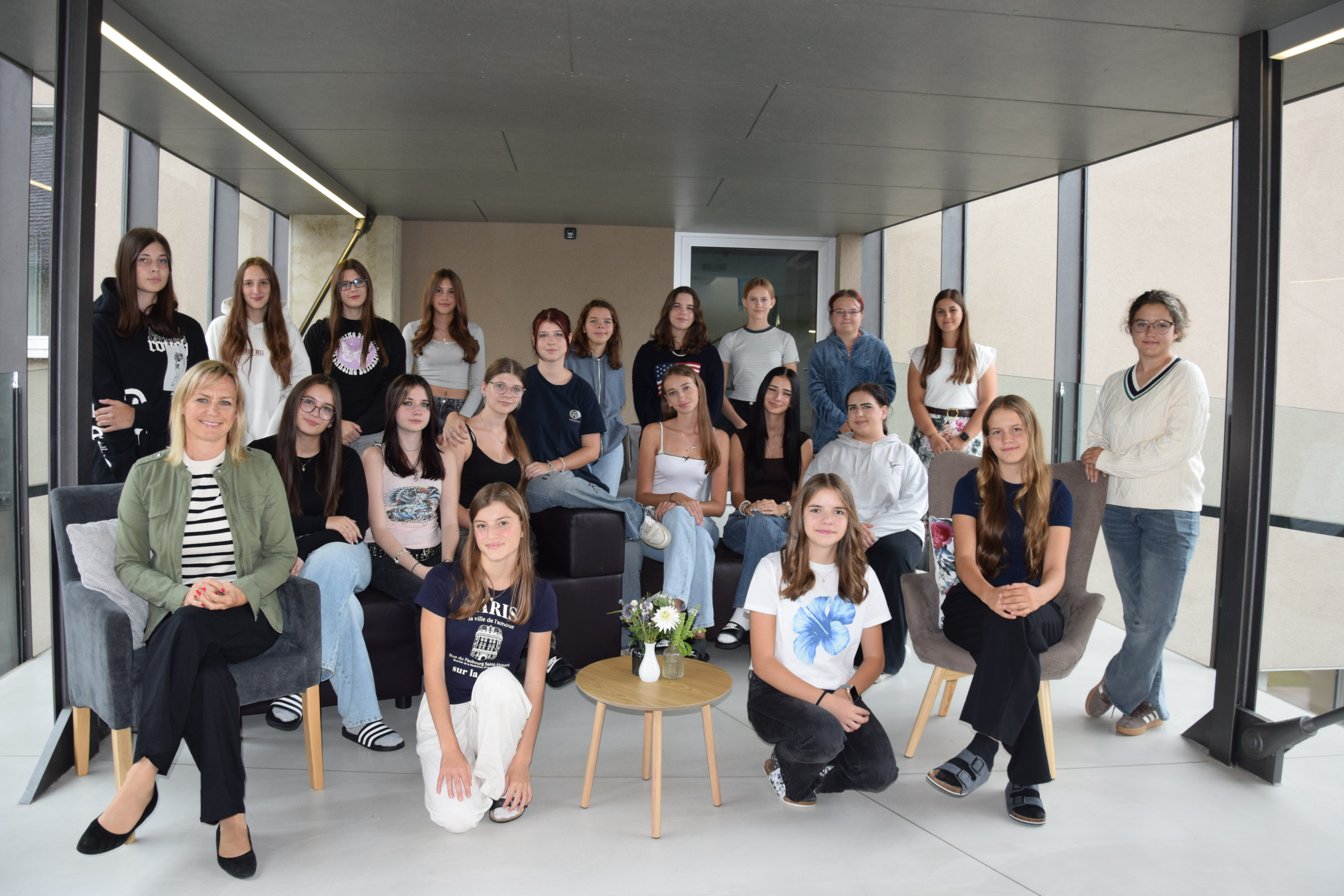 Die SchülerInnen der 2 B Klasse und ihre Klassenlehrerin stehen vor dem Schuleingang für ein Gruppenfoto.