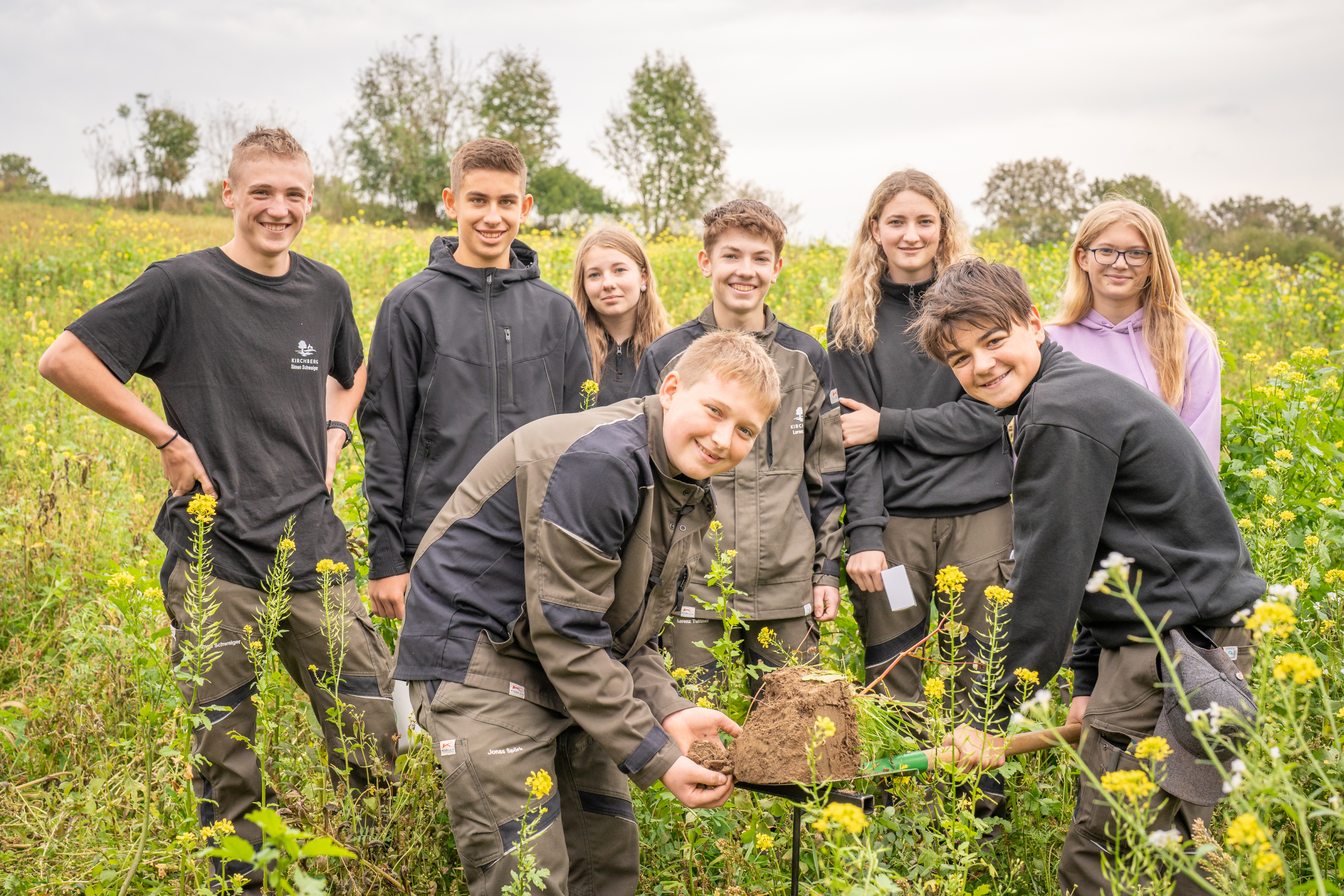Am Bild sieht man Schülerinnen und Schüler, welche mit dem Spaten eine Bodenprobe gezogen haben.