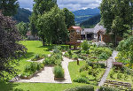 Gepflegter Kräutergarten mit erhöhten Beeten und einem hölzernen Aussichtsturm in grüner Landschaft. Kräutermensch