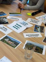 Nahaufnahme eines Tisches mit ausgedruckten Materialien. Im Fokus stehen Blätter mit Texten und Bildern zu sozialen Themen.