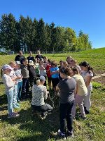 Im Freien: Kinder*innen und Jugendliche versammeln sich um einen Baum, im Rahmen des Pflanzprojektes.