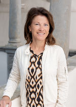 Dame mit weißer Jacke und dunklen, mittellangen Haaren vor hellgrauem Hintergrund