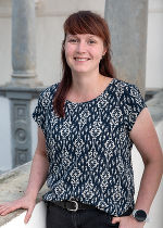Dame mit dunklen langen Haaren, gemusterten Shirt vor hellgrauem Hintergrund