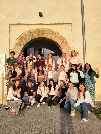 Gruppe von Personen posiert vor einem steinernen Rundbogen eines hellen Gebäudes.