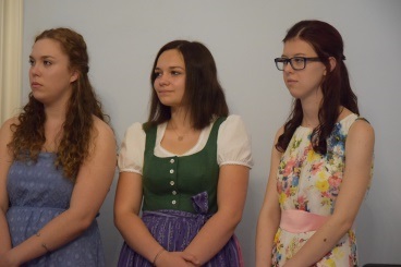 Drei Schülerinnen stehen vor einer weisen Wand und warten