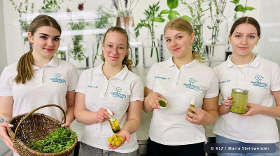 Vier Schülerinnen mit Kräutern und frisch hergestellten Kräuterprodukten